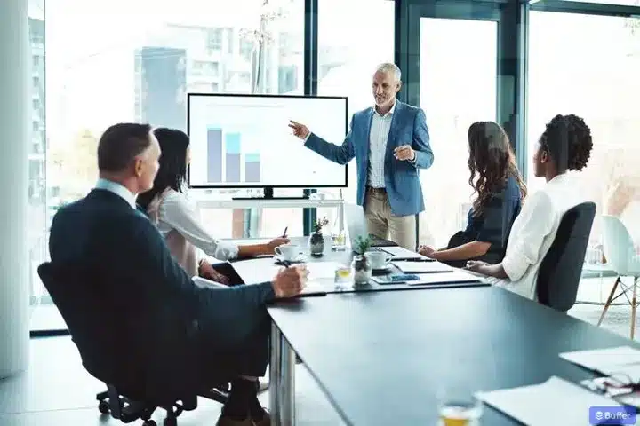 A virtual CFO giving a presentation to a diverse group of colleagues in a modern office setting with a graph displayed on a screen by SATS INTERNATIONAL